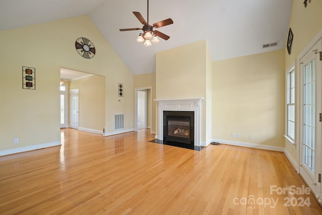 unfurnished living room with high vaulted ceiling, light wood-type flooring, a fireplace with flush hearth, and visible vents