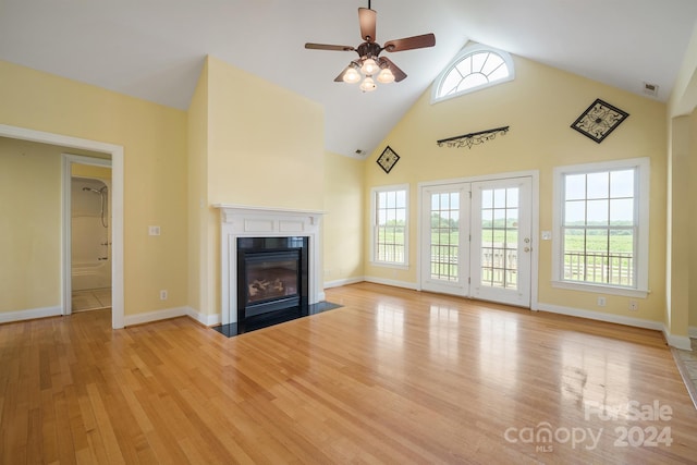 unfurnished living room featuring high vaulted ceiling, a fireplace with flush hearth, visible vents, baseboards, and light wood finished floors