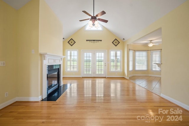 unfurnished living room featuring ceiling fan, high vaulted ceiling, wood finished floors, and a high end fireplace