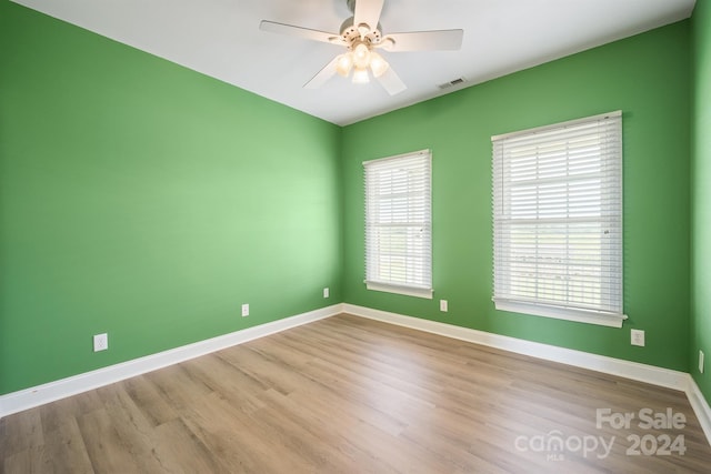 spare room with baseboards, visible vents, ceiling fan, and wood finished floors