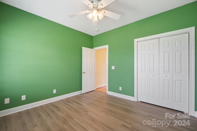 unfurnished bedroom with ceiling fan, a closet, wood finished floors, and baseboards