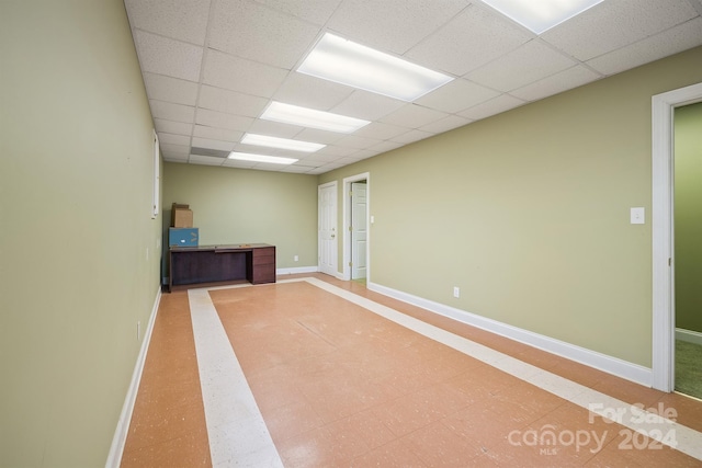 spare room featuring a drop ceiling and baseboards