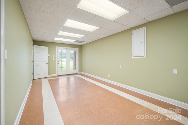 unfurnished room with french doors, a paneled ceiling, and baseboards