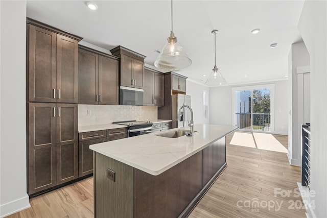 kitchen featuring dark brown cabinetry, sink, stainless steel appliances, light hardwood / wood-style flooring, and decorative light fixtures