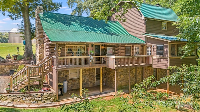 rear view of property featuring a wooden deck and a patio