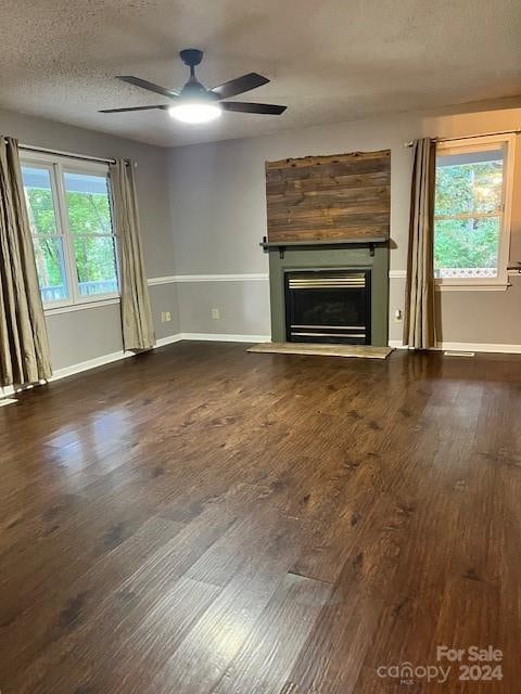 unfurnished living room featuring ceiling fan, a textured ceiling, and dark hardwood / wood-style flooring