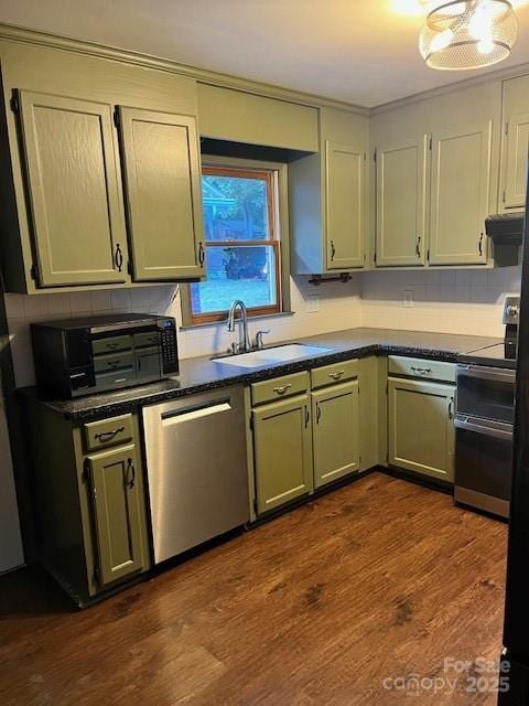 kitchen featuring decorative backsplash, dark wood finished floors, dark countertops, stainless steel appliances, and a sink