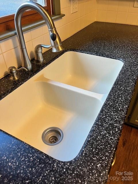 interior details featuring dark stone counters, a sink, and decorative backsplash