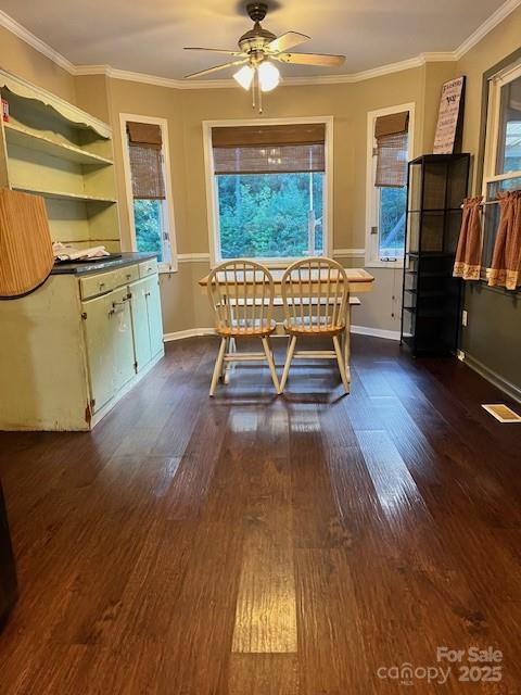 dining area with dark wood-style flooring, a healthy amount of sunlight, and crown molding