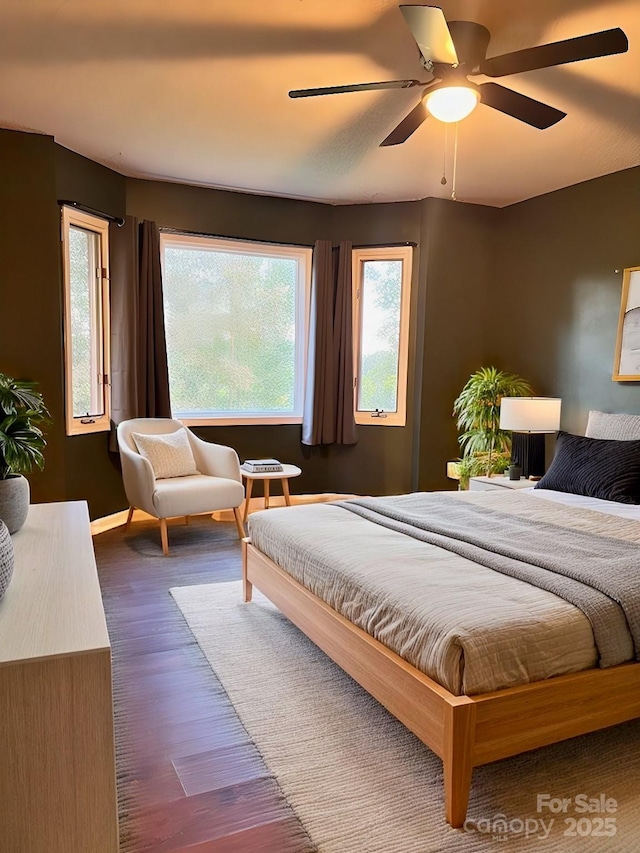 bedroom featuring ceiling fan, multiple windows, and dark wood-style flooring