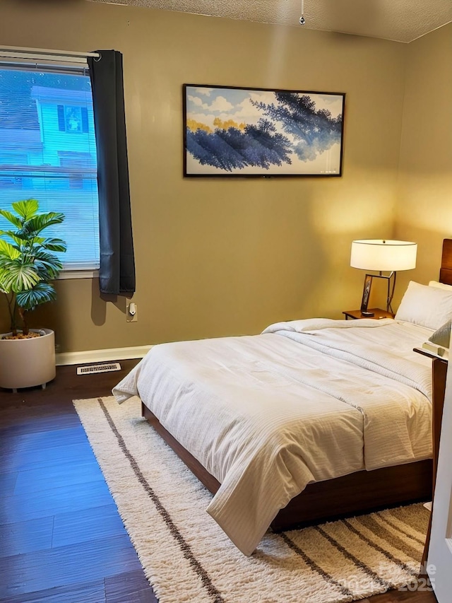 bedroom featuring wood finished floors, visible vents, and baseboards