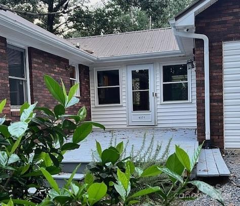 view of exterior entry featuring metal roof and brick siding