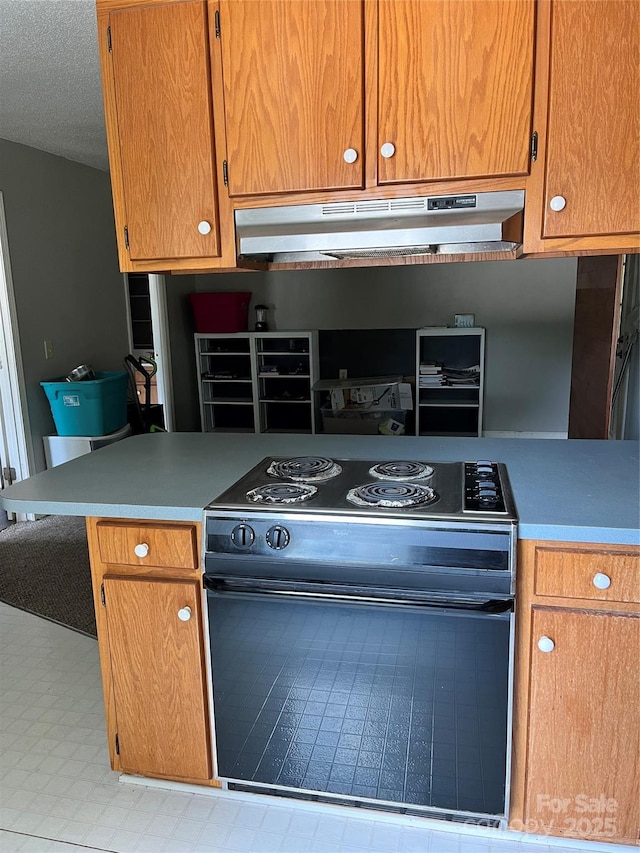 kitchen featuring light countertops, a textured ceiling, black range with electric cooktop, under cabinet range hood, and tile patterned floors