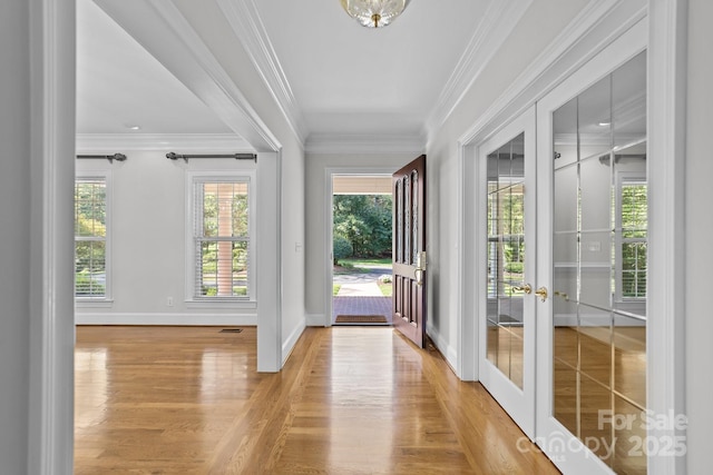 doorway to outside with light hardwood / wood-style flooring, ornamental molding, french doors, and a healthy amount of sunlight