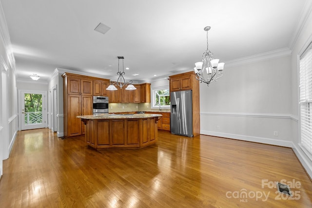 kitchen featuring stainless steel fridge, a center island, a notable chandelier, hanging light fixtures, and sink