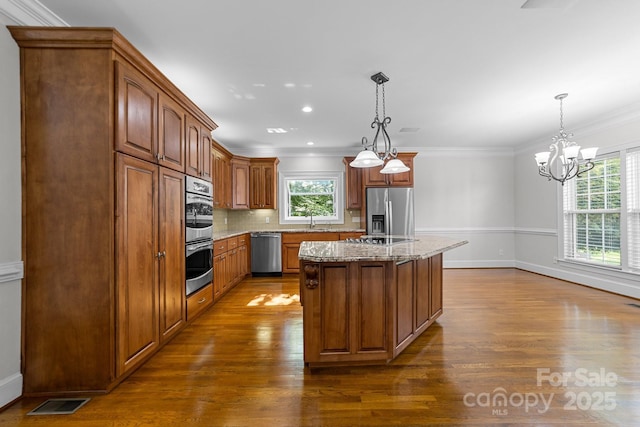 kitchen featuring appliances with stainless steel finishes, sink, a kitchen island, and decorative light fixtures