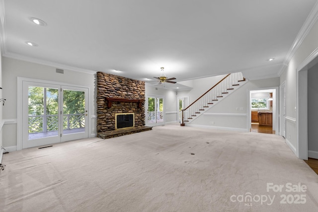 unfurnished living room with light carpet, ceiling fan, crown molding, and a stone fireplace