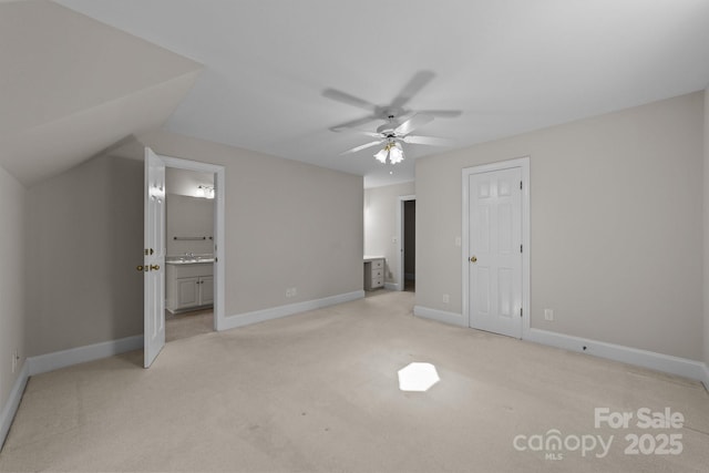 unfurnished bedroom featuring vaulted ceiling, ceiling fan, connected bathroom, and light colored carpet