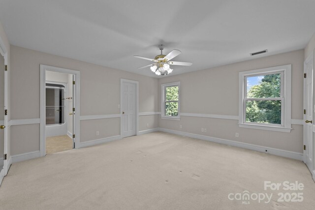 unfurnished bedroom with ceiling fan, light colored carpet, and connected bathroom