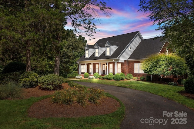 cape cod house with brick siding and a lawn