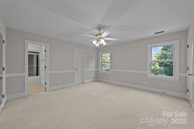 unfurnished room featuring light colored carpet, visible vents, ceiling fan, and baseboards