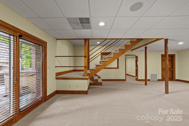 below grade area with stairway, baseboards, visible vents, and light colored carpet