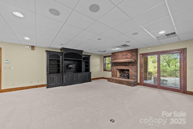 unfurnished living room featuring carpet floors, visible vents, a brick fireplace, a drop ceiling, and baseboards