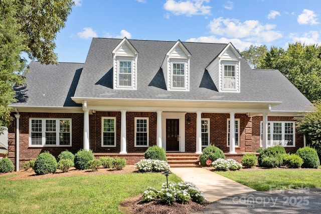 cape cod-style house featuring brick siding, a front lawn, and a shingled roof