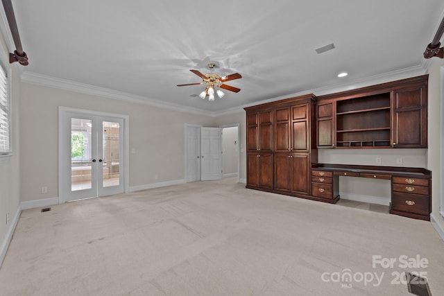 interior space with baseboards, ornamental molding, built in desk, and light colored carpet