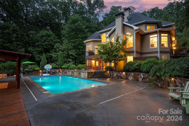 pool at dusk with a patio area