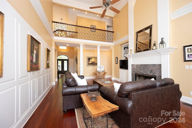 living room featuring dark hardwood / wood-style flooring, a premium fireplace, decorative columns, and french doors