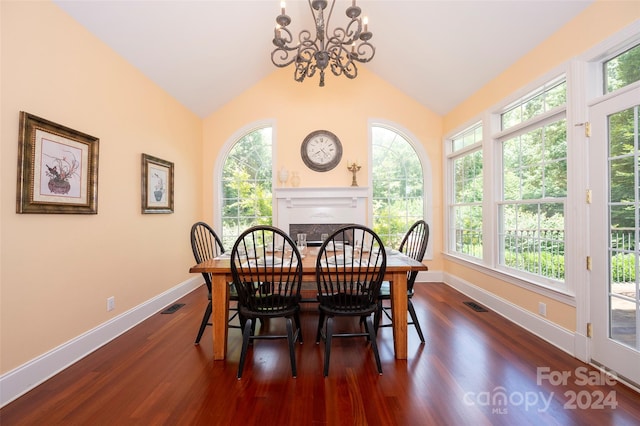 dining room featuring a healthy amount of sunlight, lofted ceiling, dark wood-type flooring, and a chandelier