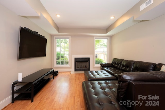 living room featuring a tray ceiling and light hardwood / wood-style floors