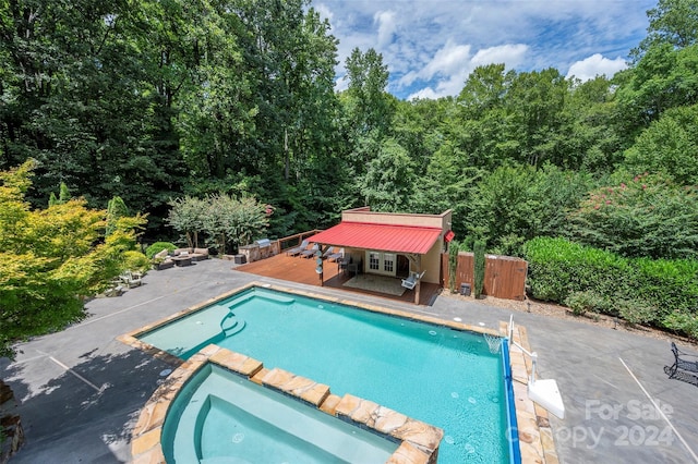 view of pool featuring a wooden deck, a patio area, an outdoor structure, and an in ground hot tub