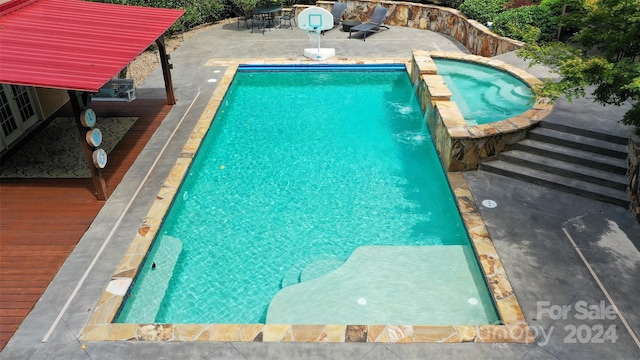 view of swimming pool featuring an in ground hot tub, pool water feature, and a wooden deck