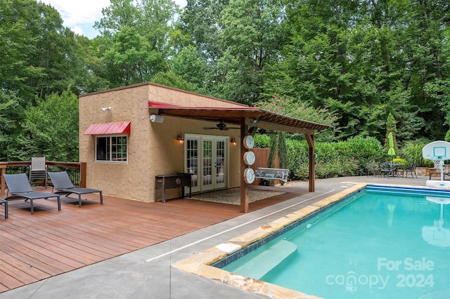 view of pool with french doors, ceiling fan, a wooden deck, and a patio area