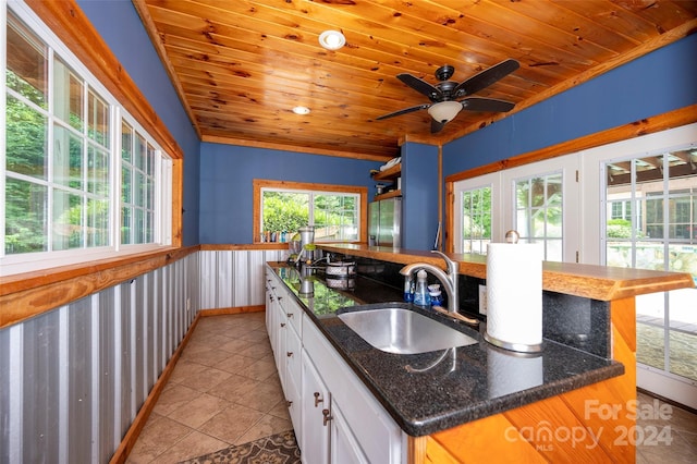 kitchen featuring white cabinetry, sink, a center island with sink, and wooden ceiling