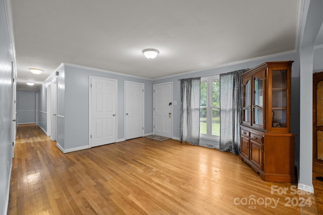 interior space with ornamental molding and light hardwood / wood-style floors