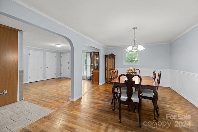 dining room with an inviting chandelier, crown molding, and light hardwood / wood-style flooring