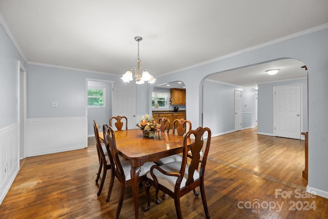 dining area with crown molding, a notable chandelier, and hardwood / wood-style floors