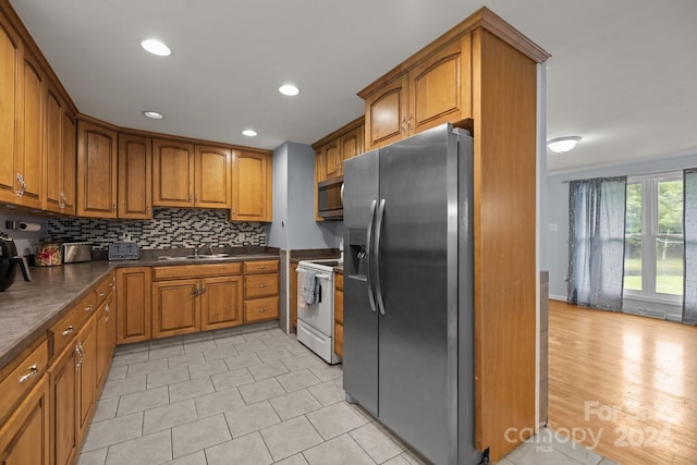 kitchen featuring appliances with stainless steel finishes, tasteful backsplash, light hardwood / wood-style flooring, and sink