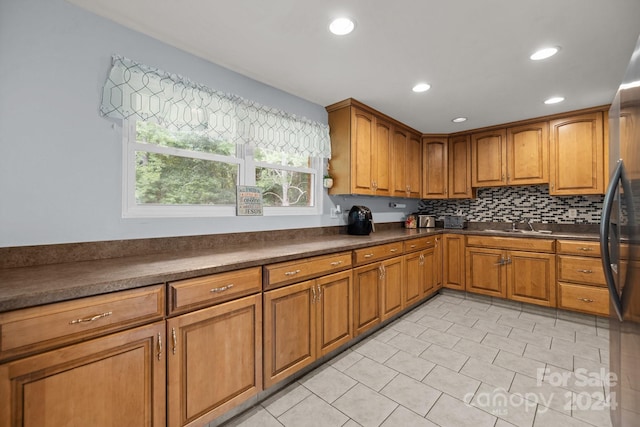 kitchen featuring black refrigerator, backsplash, and sink