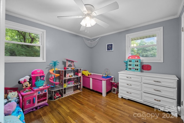 rec room with ceiling fan, plenty of natural light, dark hardwood / wood-style floors, and ornamental molding