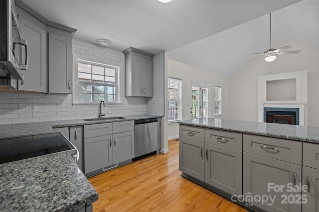 kitchen featuring gray cabinetry, backsplash, sink, vaulted ceiling, and appliances with stainless steel finishes