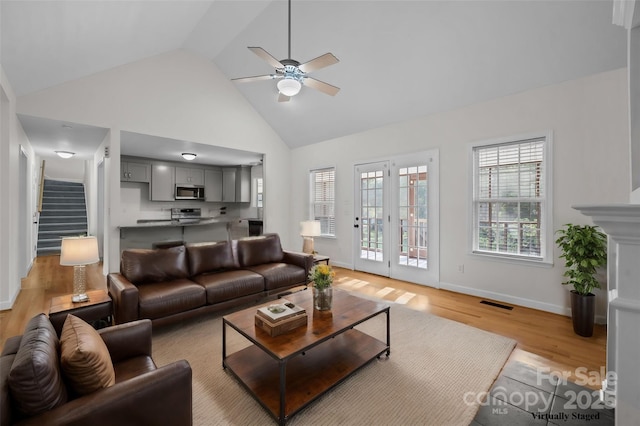 living room with light hardwood / wood-style floors, high vaulted ceiling, and ceiling fan