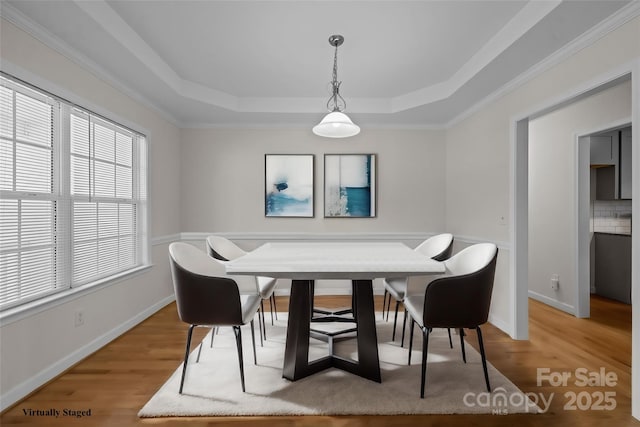 dining area with hardwood / wood-style flooring, crown molding, and a tray ceiling