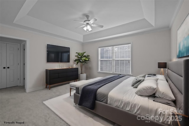 carpeted bedroom featuring ceiling fan, a raised ceiling, and crown molding