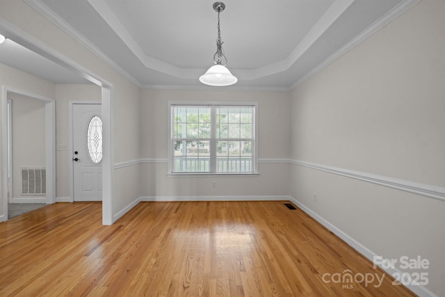 interior space featuring light hardwood / wood-style floors, a raised ceiling, and crown molding