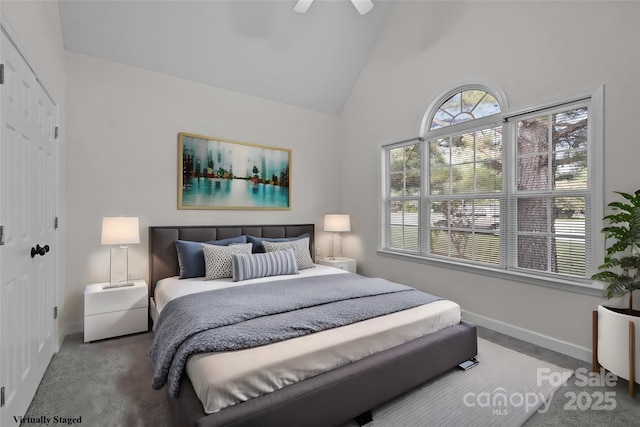 carpeted bedroom with ceiling fan, high vaulted ceiling, and a closet