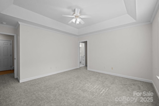 empty room with carpet, a raised ceiling, and ceiling fan